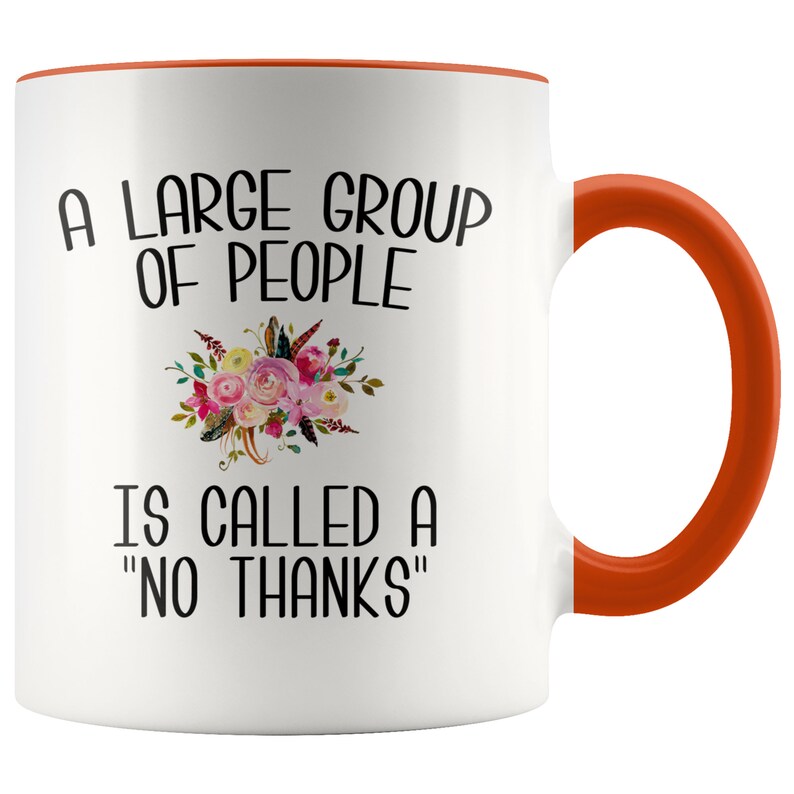 May include: White ceramic coffee mug with an orange rim and handle. The mug features a floral design and the text "A large group of people is called a "no thanks""
