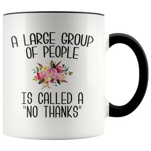 May include: White ceramic coffee mug with a black rim and handle. The mug features black text that reads "A large group of people is called a "no thanks"". A floral design is above the text.