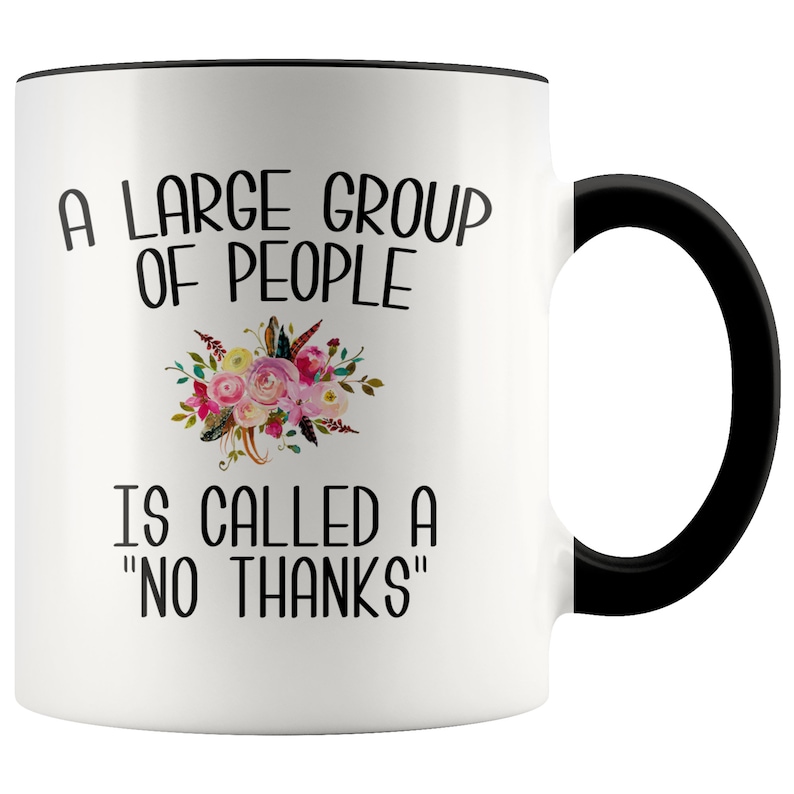 May include: White ceramic coffee mug with a black rim and handle. The mug features black text that reads "A large group of people is called a "no thanks"". A floral design is above the text.
