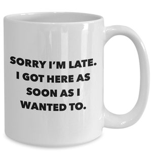 May include: White ceramic coffee mug with black text that reads "Sorry I'm late. I got here as soon as I wanted to."