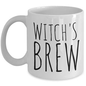 May include: White ceramic coffee mug with black text that reads "Witch's Brew".
