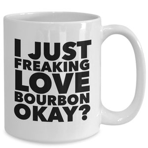 Pu&ograve; includere: Tazza in ceramica bianca con manico curvo. La tazza presenta il testo "I JUST FREAKING LOVE BOURBON OKAY?" in grassetto nero. Progettata per bevande calde.