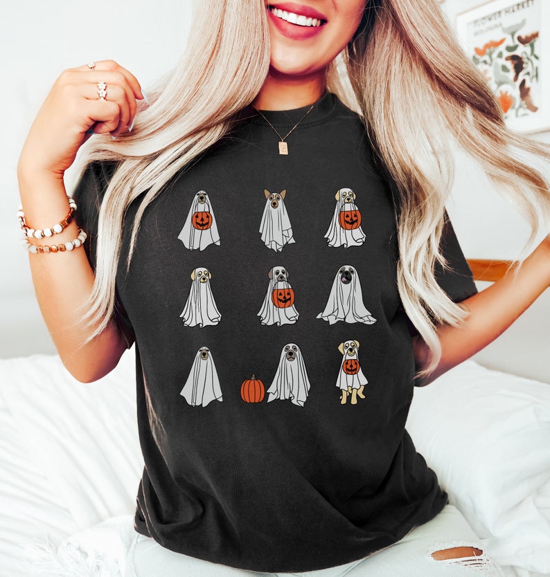 Peut inclure: Un t-shirt noir avec un motif de chiens habill&eacute;s en fant&ocirc;mes pour Halloween. Les chiens tiennent des citrouilles et portent des costumes de fant&ocirc;mes.