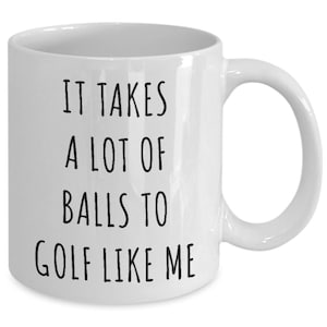 May include: White ceramic coffee mug with black text that reads "It takes a lot of balls to golf like me."