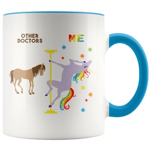 May include: White ceramic coffee mug with a blue rim and handle. The mug features a graphic of a unicorn doing a pole dance with the text "ME" above it. A brown horse is on the left side of the mug with the text "OTHER DOCTORS" above it.