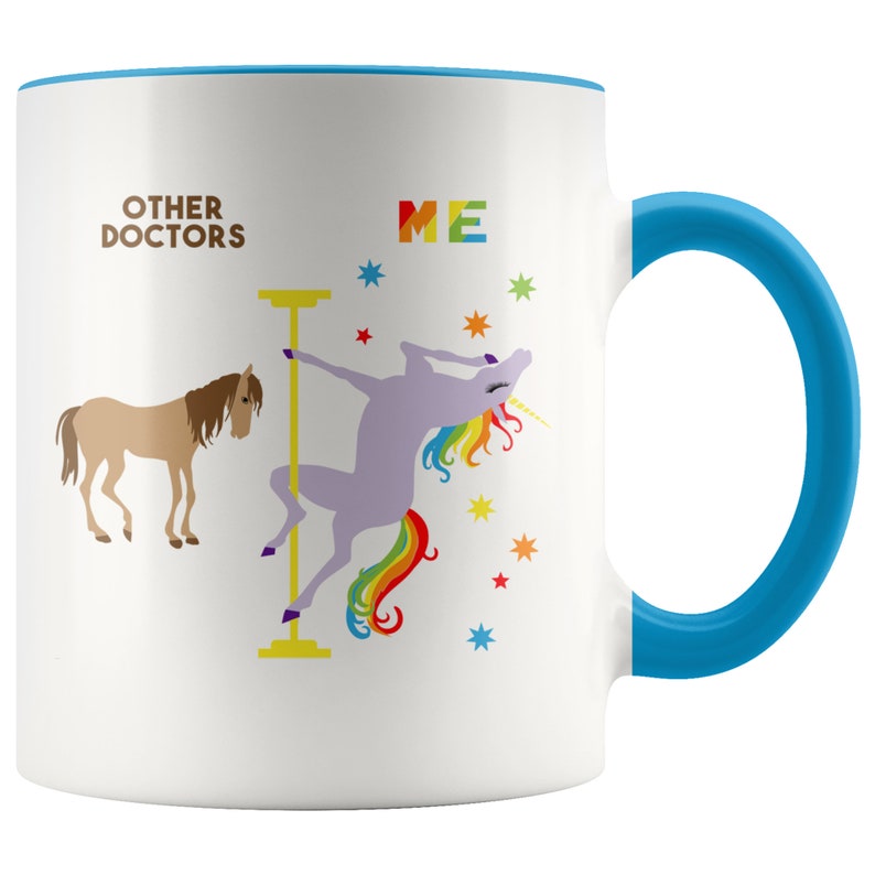 May include: White ceramic coffee mug with a blue rim and handle. The mug features a graphic of a unicorn doing a pole dance with the text "ME" above it. A brown horse is on the left side of the mug with the text "OTHER DOCTORS" above it.