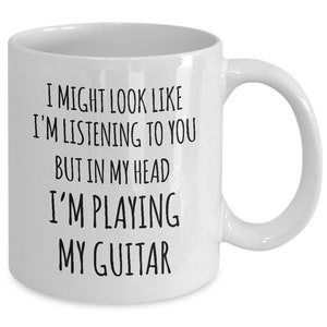 May include: White ceramic coffee mug with black text that reads "I might look like I'm listening to you but in my head I'm playing my guitar".