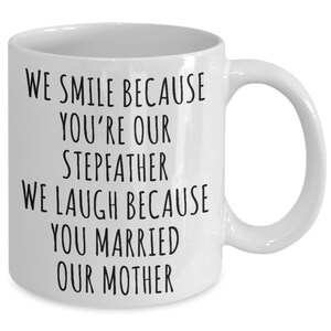 May include: White ceramic coffee mug with black text that reads "We smile because you're our stepfather. We laugh because you married our mother."