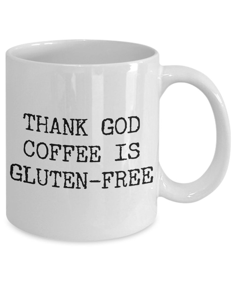 Puede incluir: Taza de caf&eacute; de cer&aacute;mica blanca con texto negro que dice "THANK GOD COFFEE IS GLUTEN-FREE".