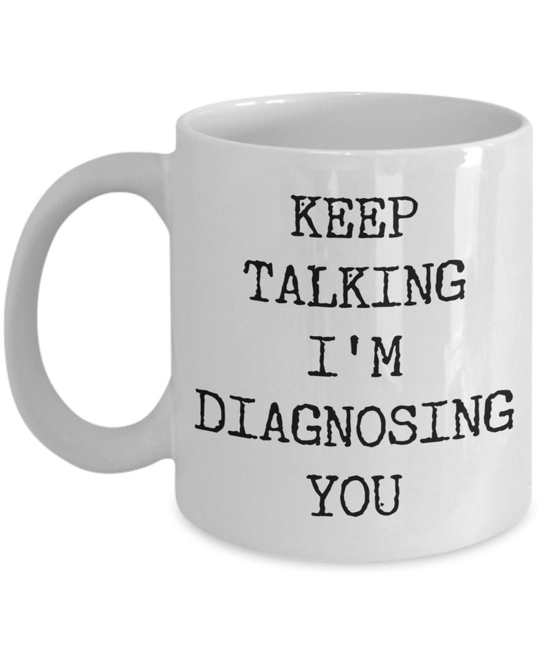 May include: White ceramic coffee mug with black text that reads "Keep Talking I'm Diagnosing You".