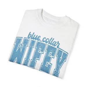 May include: White t-shirt with a blue distressed graphic that says "blue collar wifey".