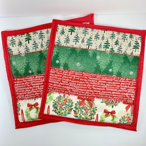 May include: Two square Christmas-themed pot holders with a red border. The fabric features sections of Christmas trees, green speckled patterns, red script, and wreaths with red bows. The pot holders are designed for kitchen use.