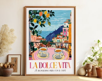 May include: A colorful illustration of a balcony overlooking a seaside town with two cups of coffee on a pink saucer. The text "LA DOLCE VITA" is written in pink and orange letters with the caption "A BUONGIORNO INIZIA CON IL CAFFE".