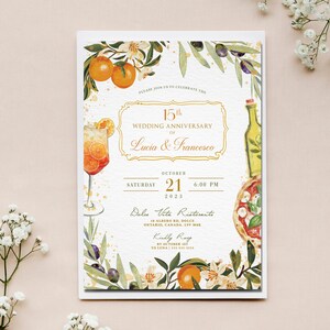 May include: A white invitation card with gold lettering announcing a 15th wedding anniversary for Lucia & Francesco. The invitation features a watercolor illustration of a glass of Aperol Spritz, a bottle of olive oil, a pizza, and orange blossoms. The event will be held on Saturday, October 21st, 2023 at 6:00 PM at Dolce Vita Ristorante, 18 Albero Rd, Dolce, Ontario, Canada, LSV Mak.