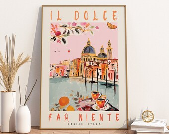 May include: A framed art print with a vibrant illustration of Venice, Italy, displaying the words "IL DOLCE FAR NIENTE". The artwork showcases buildings, canals, and a domed church, in pink, orange, and blue hues. Two coffee cups are in the foreground.