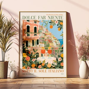 Op de afbeelding: Een kleurrijke poster met de tekst "Dolce Far Niente" en "Sotto Il Sole Italiano" in een vintage stijl. De poster toont een uitzicht op een kleurrijk Italiaans stadje met een balkon met uitzicht op de oceaan. Twee glazen sinaasappelsap staan op een tafel met een citrusboom op de voorgrond.