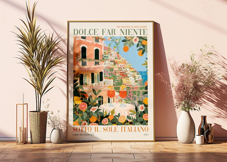 Op de afbeelding: Een kleurrijke poster met de tekst "Dolce Far Niente" en "Sotto Il Sole Italiano" in een vintage stijl. De poster toont een uitzicht op een kleurrijk Italiaans stadje met een balkon met uitzicht op de oceaan. Twee glazen sinaasappelsap staan op een tafel met een citrusboom op de voorgrond.