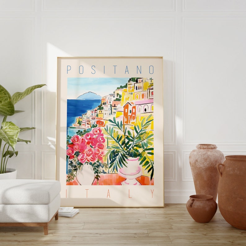 Może przedstawiać: Kolorowy plakat z tekstem "POSITANO WŁOCHY" w niebieskich literach. Plakat przedstawia akwarelę przedstawiającą nadmorskie miasto z kolorowymi budynkami i błękitnym oceanem.