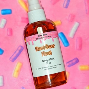 Puede incluir: Botella transparente de bruma corporal con una etiqueta blanca que dice "Root Beer Float Body Mist 2 oz.". La botella contiene un líquido marrón y tiene un pulverizador blanco. El fondo es rosa con chispas de colores.