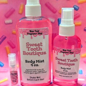 May include: Pink body mists from Nose Food Fragrance Shop. The bottles are labeled "Sweet Tooth Boutique" and come in 4 oz and 2 oz sizes, with a sample size. The labels include ingredients and instructions to shake before use.
