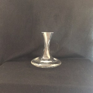 May include: A clear glass wine decanter with a wide base and a tall, narrow neck.