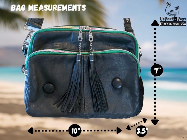Puede incluir: Bolso de cuero negro con ribete verde y cremalleras plateadas. El bolso tiene dos borlas negras y dos botones negros redondos. El bolso mide 25,4 cm de ancho, 17,8 cm de alto y 8,9 cm de profundidad. El texto "BAG MEASUREMENTS" est&aacute; en la parte superior.