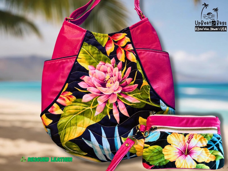 May include: A pink and floral tote bag and matching wristlet. The tote bag has a large floral design with pink, yellow, and green accents. The wristlet features a similar floral pattern. The bags are made with rescued leather.