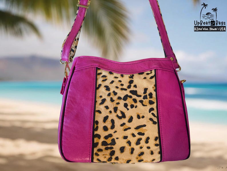 May include: A fuchsia-colored handbag with a leopard print center panel and a matching strap. The bag has gold-colored hardware and the text "UpBeat Bags Kāne'ohe, Hawai'i USA" is visible in the upper right corner.