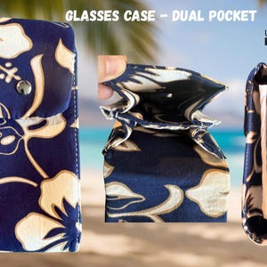 May include: A navy blue glasses case with a dual pocket design. The case features a floral pattern in white and tan. The case is shown in three views: closed, open, and side view. The text "GLASSES CASE - DUAL POCKET" is at the top.