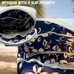 May include: Close-up of a light gray bag interior with three slip pockets. The interior features a navy blue floral pattern with white and cream-colored flowers. The bag has a white zipper and is from UpBeat Bags, Kona, Hawaii, USA.
