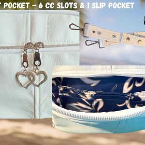 May include: White leather bag with silver heart-shaped zipper pulls. Features a front pocket with 6 card slots and 1 slip pocket. Includes a detachable white strap with silver hardware. The interior has a blue floral pattern.