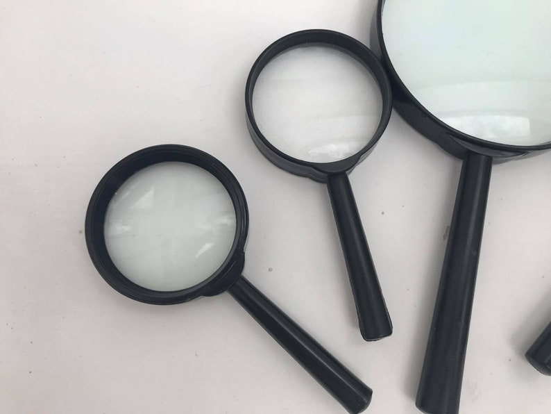 K&ouml;nnte beinhalten: Drei schwarze Handlupen in verschiedenen Gr&ouml;&szlig;en. Die Lupen haben schwarze Kunststoffgriffe und klare Glaslinsen.