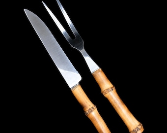 May include: A stainless steel serrated knife and a two-pronged carving fork, both featuring natural light brown bamboo handles with distinct segmented nodes and a polished metallic finish on the blades and tines against a black background.