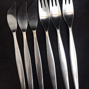 May include: Set of six silver flatware pieces, including three forks and three knives. The flatware has a modern, minimalist design with sleek, straight handles.