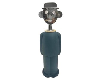 May include: A blue and silver bottle opener shaped like a person wearing a hat. The person has a smiling face with two eyes and a mouth.