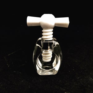 Puede incluir: Un cascanueces de plástico blanco con un cuerpo de plástico transparente. El cascanueces tiene un mango con dos alas blancas.