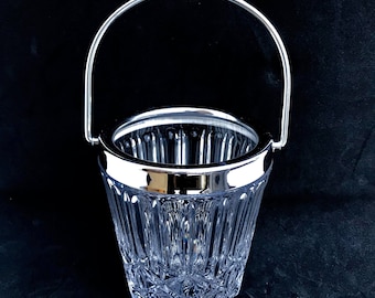 May include: A clear glass ice bucket with a silver metal handle and rim. The bucket has a diamond pattern.
