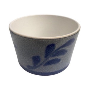 May include: A grey ceramic planter with a blue floral design. The planter has a white interior and a textured exterior.