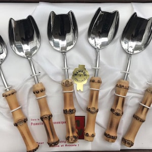 May include: Set of six silver spoons with bamboo handles. The spoons have a tulip-shaped bowl and the handles are decorated with a brown and white pattern. The spoons are in a box with a label that says "Bambou Veritable".