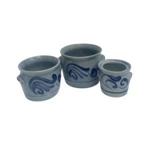 Op de afbeelding: Drie blauwe en witte keramische kommen met een blauw en wit swirl-ontwerp. De kommen zijn van verschillende groottes en zijn gerangschikt in een rij van de grootste naar de kleinste.