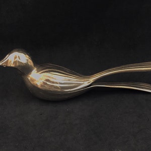May include: A silver bird-shaped nutcracker with a detailed design. The nutcracker is open and ready to crack nuts.