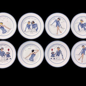 Puede incluir: Un juego de ocho platos de cerámica blanca con borde azul, cada uno con una ilustración única de figuras con camisas de rayas azules y blancas y gorros de marinero. Los diseños incluyen gaviotas, un globo rojo y varias poses náuticas.