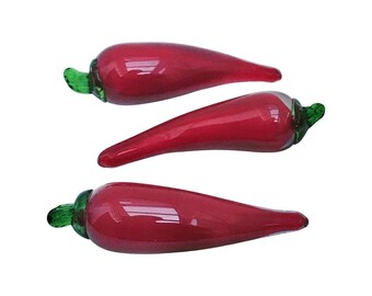 May include: Three red glass chili peppers with green stems. The peppers are arranged in a row, with the largest pepper at the top and the smallest pepper at the bottom.