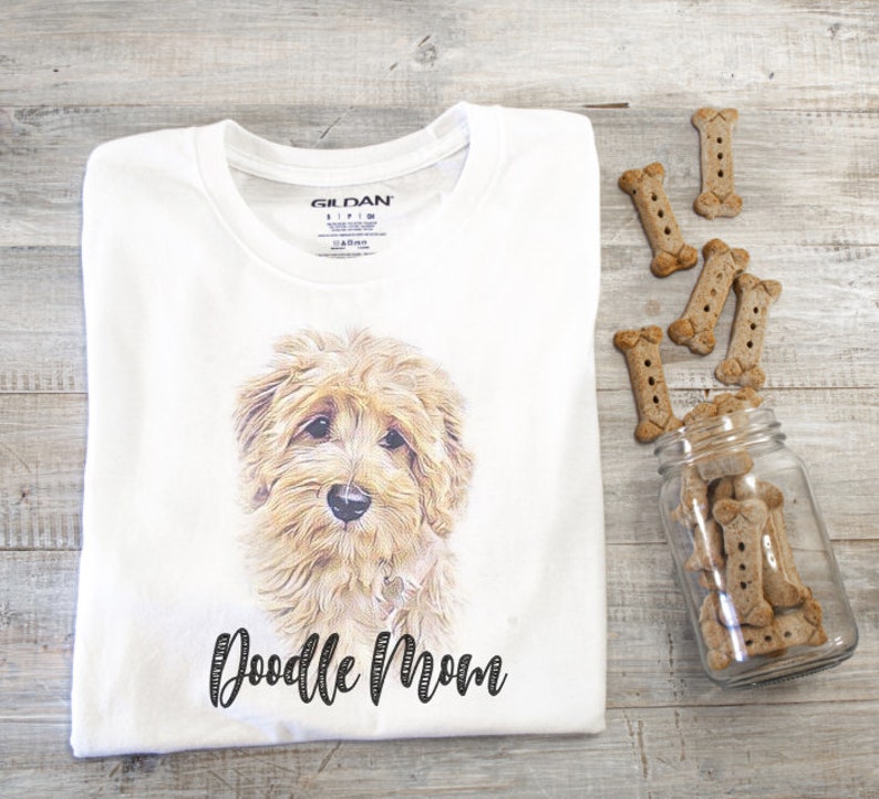 May include: White t-shirt with a doodle dog illustration and the text "Doodle Mom" printed on the front.