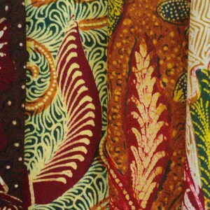 May include: Close-up of four different fabric swatches with intricate patterns. The swatches are in shades of brown, green, orange, and yellow. The patterns are floral and geometric.