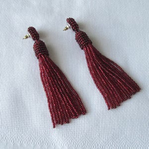 May include: A pair of long, burgundy tassel earrings. The tassels are made of small beads and are about 7.5 cm long.