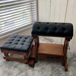 May include: A wooden furniture set consisting of a tall, arched, tufted black seat with metal hardware and a matching low, square, tufted black stool. Both pieces feature dark brown wood frames and button-tufted black upholstery on the top surfaces.