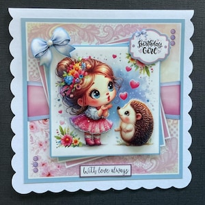 Op de afbeelding: Een handgemaakte kaart met een roze en blauwe kleurstelling. De kaart heeft een cartoonmeisje met een bloemenkrans die kusjes blaast naar een egel. De kaart zegt "Birthday Girl" en "With love always".