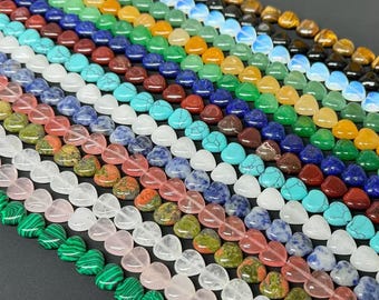 May include: A collection of heart-shaped gemstone beads arranged in parallel rows. The assortment includes various colors and textures, such as green malachite, pink rose quartz, blue turquoise, white quartz, and brown tiger eye stones.
