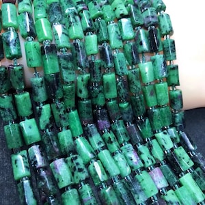May include: A strand of green, black, and pink gemstone beads. The beads are rectangular and have a rough, natural finish.